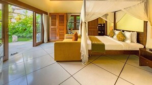 Une chambre spacieuse avec un lit à baldaquin, un canapé et une vue sur la verdure environnante.