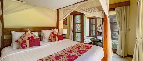 A bedroom with a canopy bed, a view of the outside, and a window with curtains.