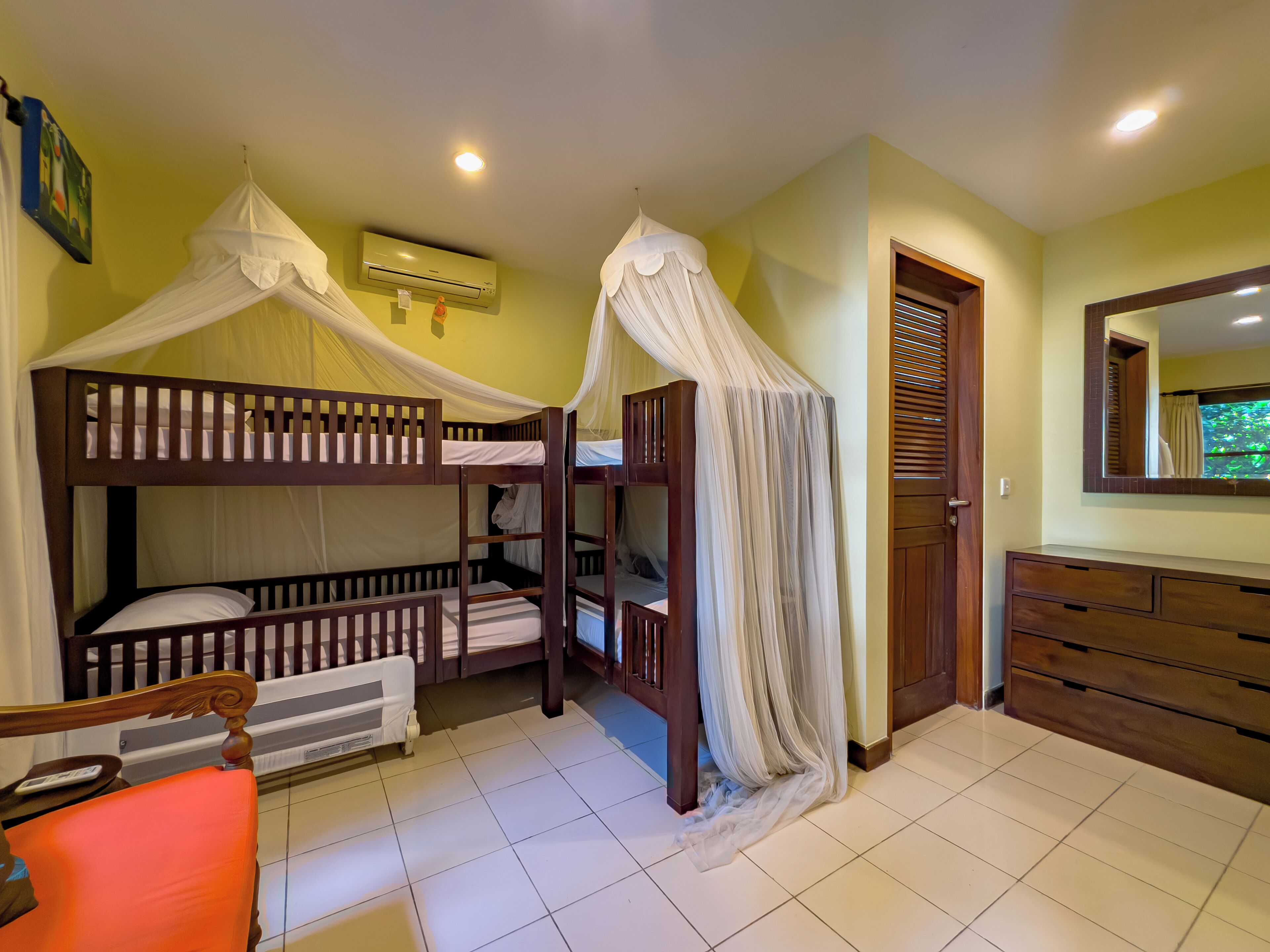 A room with bunk beds, a wooden dresser, a radiator, and a door with a window.