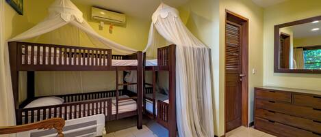 A room with bunk beds, a wooden dresser, a radiator, and a door with a window.