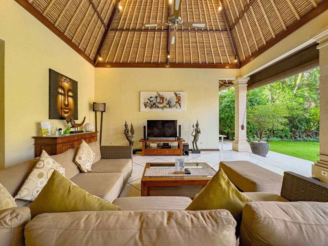 Amplia sala de estar con techo alto, televisor y vista a un jardín exuberante.