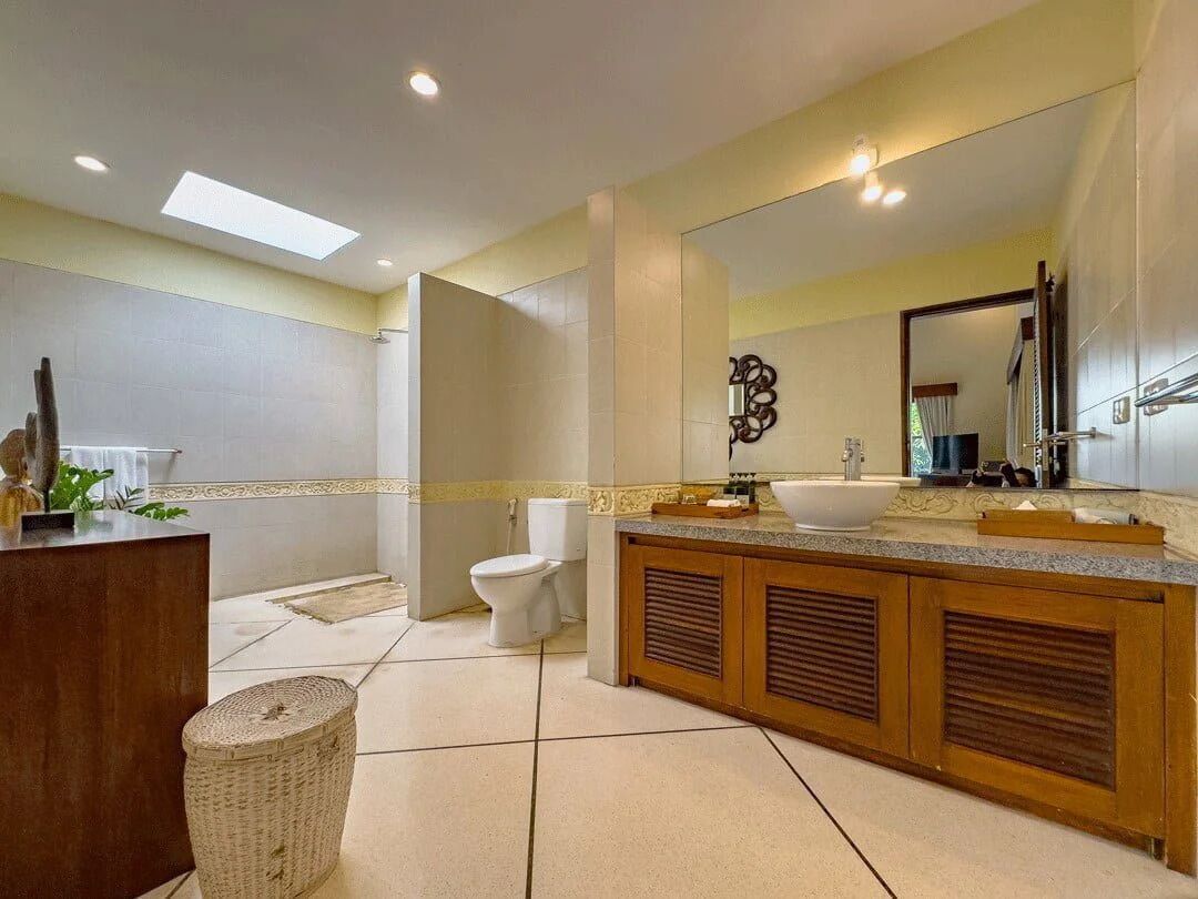 A modern bathroom with a large mirror, a wooden vanity, and a white sink.