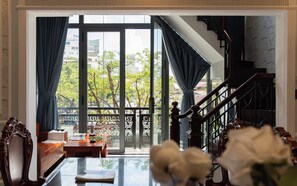 A room with a large window, a staircase, and a dining area with a table and chairs. - Ben Thanh Maison (Ho Chi Minh City)