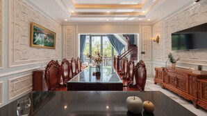 A formal dining room with a long table, ornate chairs, and a chandelier. - Ben Thanh Maison (Ho Chi Minh City)