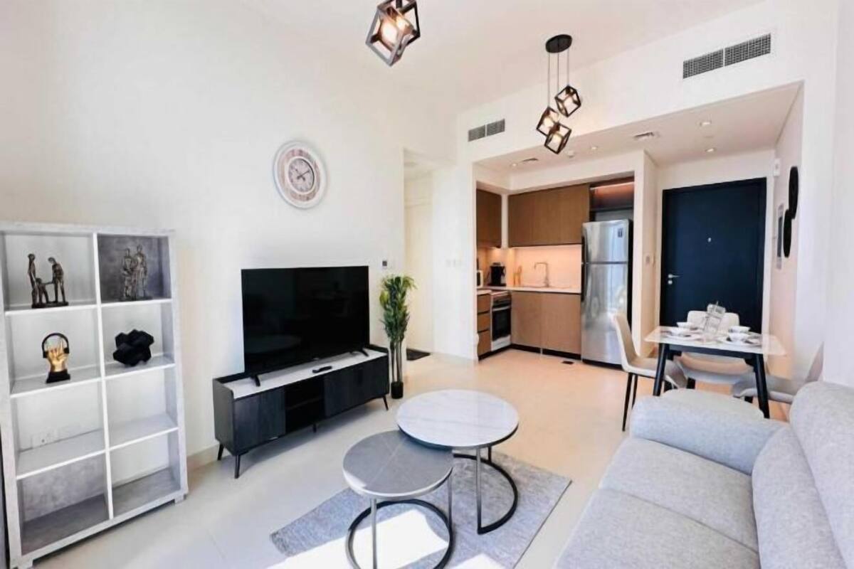 Ein modernes Wohnzimmer mit Flachbildfernseher, einem grauen Sofa, einem Couchtisch und einem Bücherregal.
