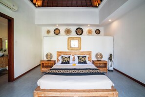 A spacious bedroom with a large bed, wooden headboard, and decorative wall art. - Island Getaway Villa (Denpasar)