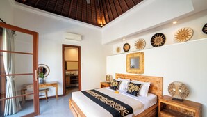 A bedroom with a wooden bed, bedside tables, a mirror, and decorative wall art. - Island Getaway Villa (Denpasar)
