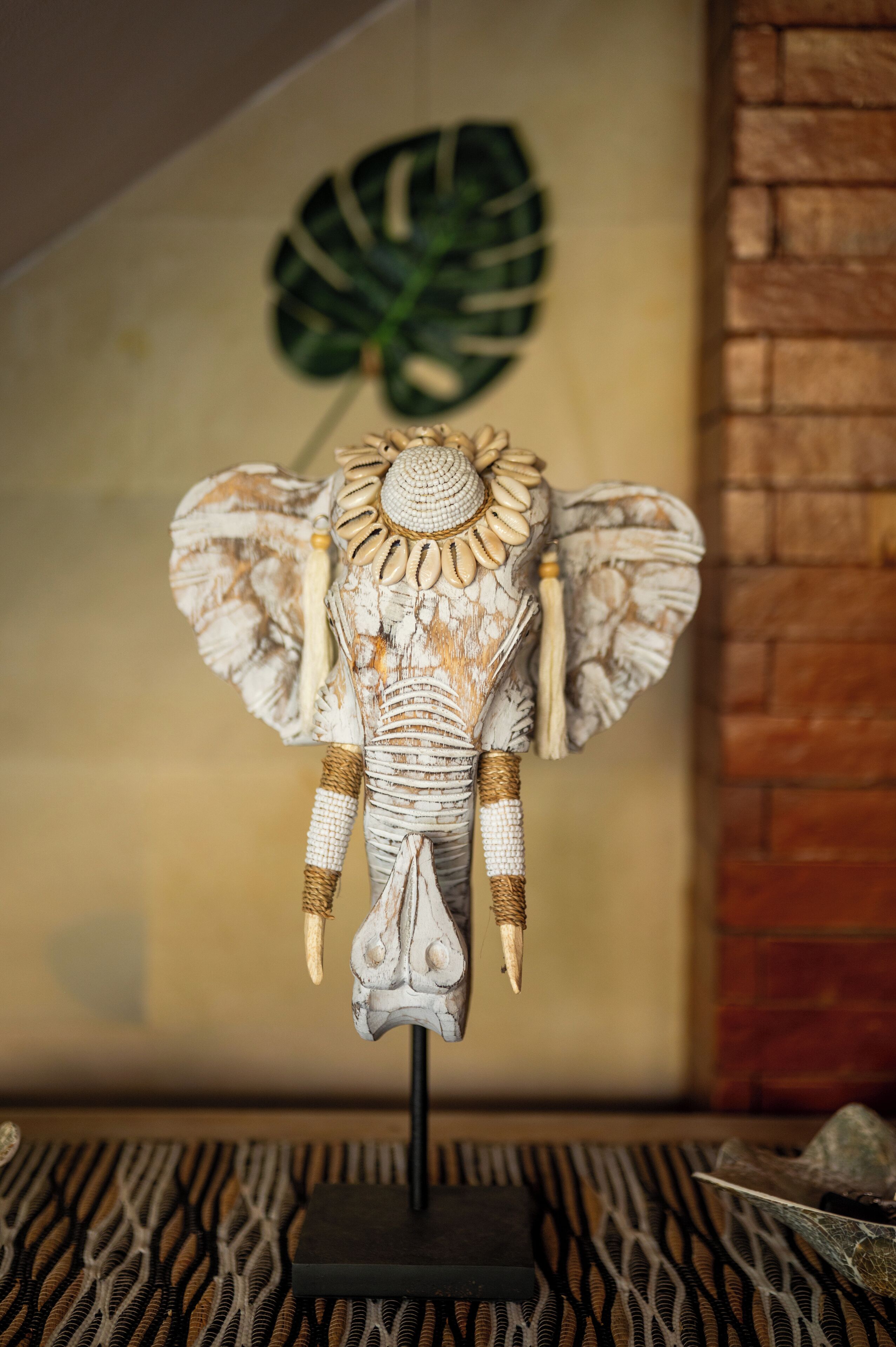 A decorative elephant head sculpture with tusks, displayed on a stand.