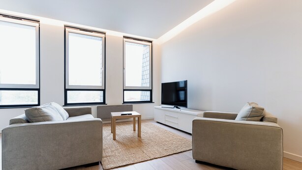 A modern living room with two sofas, a coffee table, a TV, and large windows.