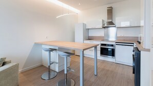 A modern kitchen with a wooden countertop, stainless steel appliances, and a bar stool.