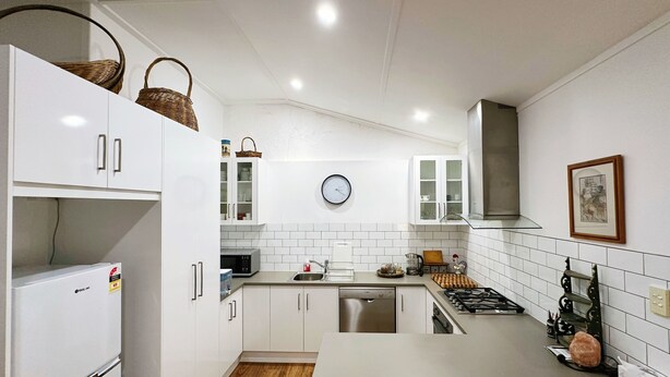 Een moderne keuken met witte kastjes, een centraal eiland, een spoelbak en een fornuis.
