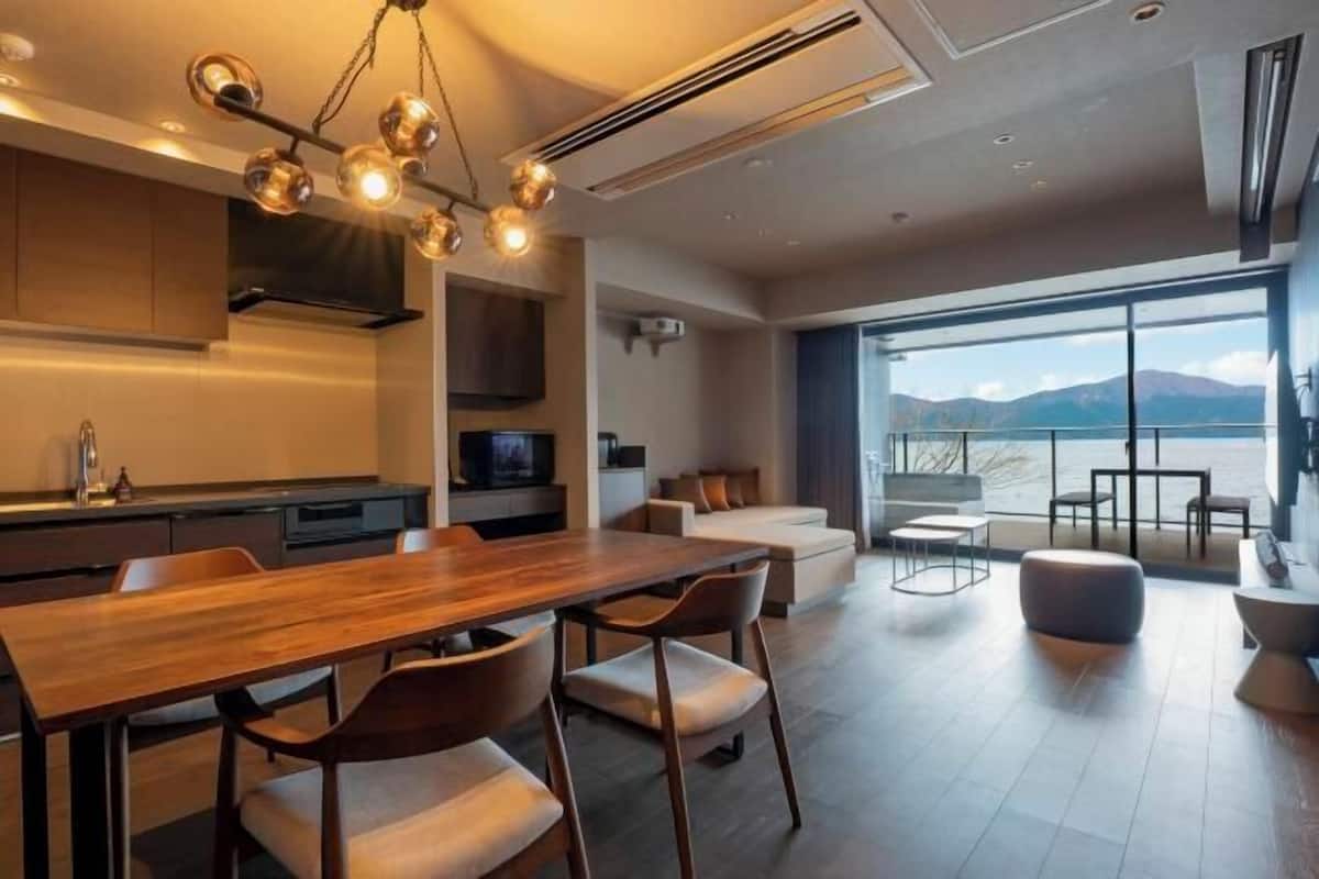 A modern kitchen with a wooden dining table, chairs, and pendant lighting.