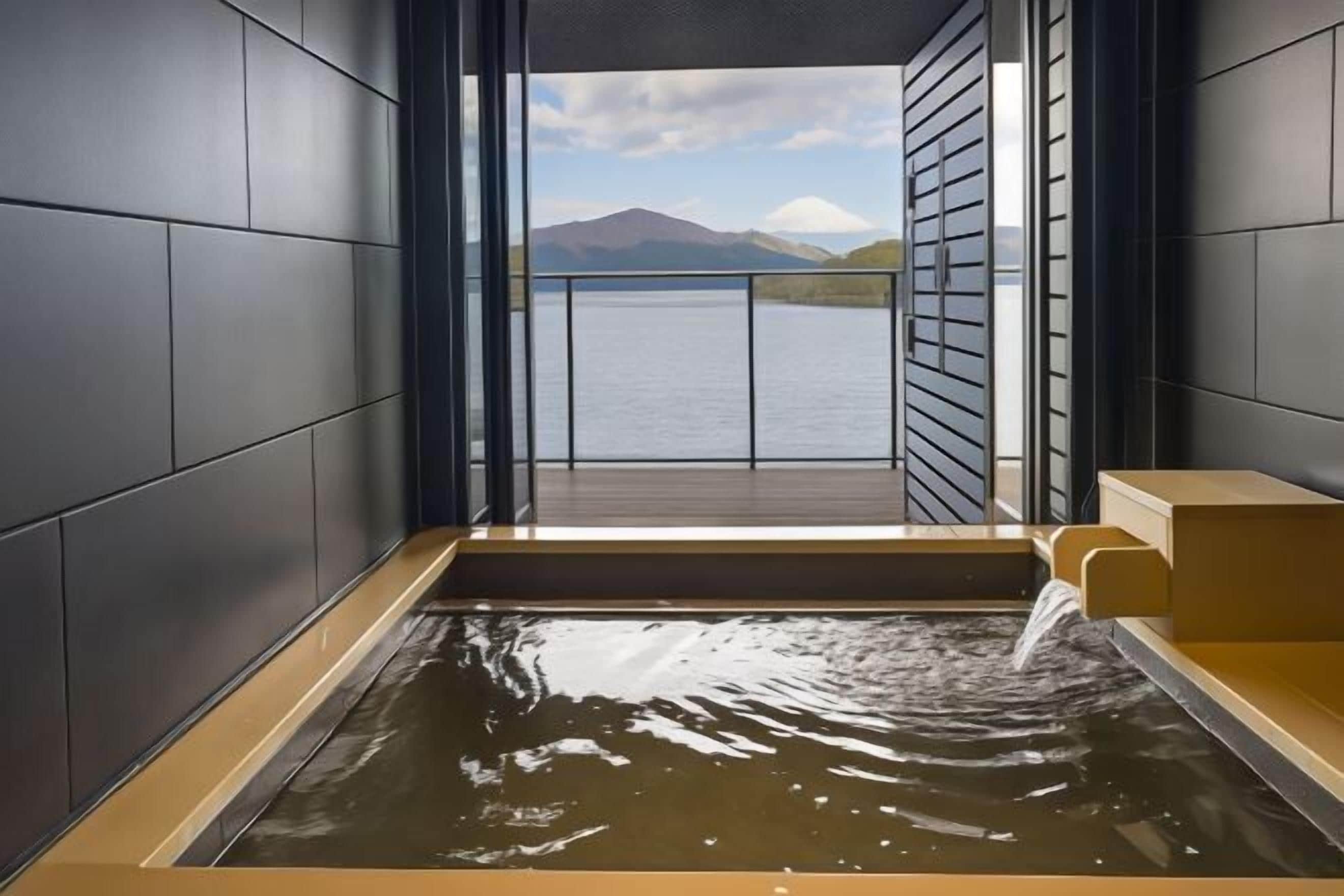 A modern spa room with a view of a lake and mountains.