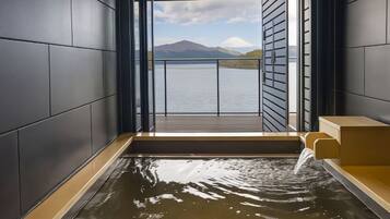 A modern spa room with a view of a lake and mountains.