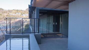 A modern outdoor area with a pool, glass doors, and a view of a hillside.