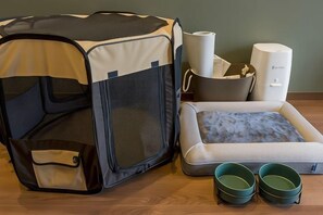 A pet bed, a pet carrier, a litter box, and two bowls on a wooden floor. - Rakuten STAY FUJIMI TERRACE Hakone Ashinoko (Hakone)