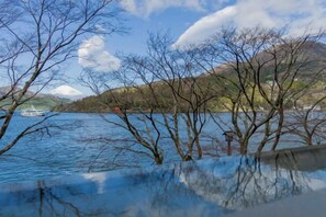 A lake with reflections of trees and a boat in the water. - Rakuten STAY FUJIMI TERRACE Hakone Ashinoko (Hakone)