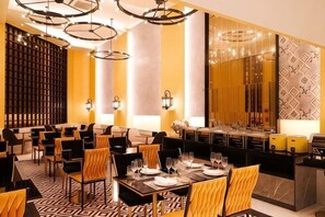 A restaurant with multiple dining tables, chairs, and a bar area. - Kastel Bangkok Hotel (Bangkok)