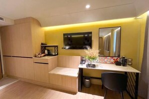 A compact kitchen with a built-in microwave, a small countertop, and a black chair. - Kastel Bangkok Hotel (Bangkok)