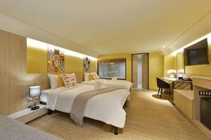 Een hotelkamer met een bed, nachtkastje, lamp en een bureau met stoel.