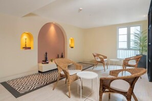 Une pièce meublée de meubles en osier, avec un tapis à motifs et une grande fenêtre.