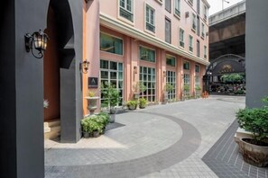 Een gebouw met een gebogen entree, potplanten en een bord met de naam 'Hotel'.