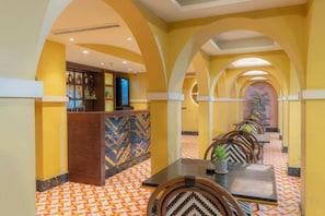 Een hotel lobby met een receptiebalie, een zithoek en een vloer met een patroon.