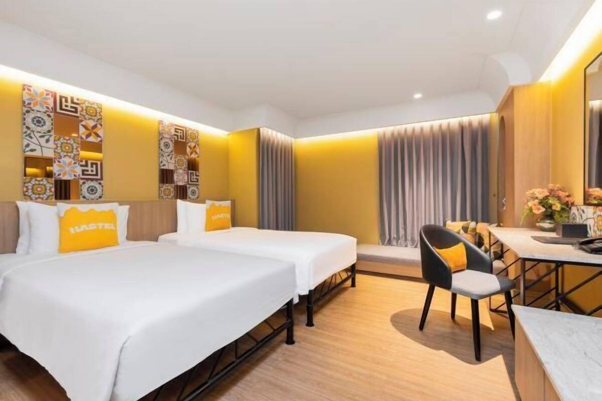 A hotel room with two beds, a desk, and a chair.