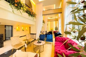 Een hotellobby met een zithoek, een receptiebalie en een groot raam.
