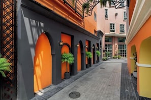 Un couloir orné d’arcades, de plantes en pot et doté d’un sol carrelé.