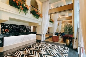 A hotel lobby with a reception desk, a black and white patterned floor, and a large potted plant. - Kastel Bangkok Hotel (Bangkok)
