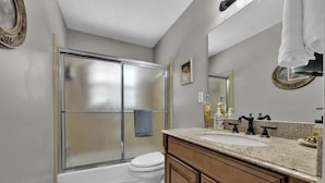 Une salle de bain équipée d’une douche, de toilettes, d’un lavabo et d’un grand miroir.