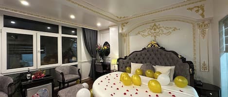 A bedroom with a large bed, a window, and a chair.
