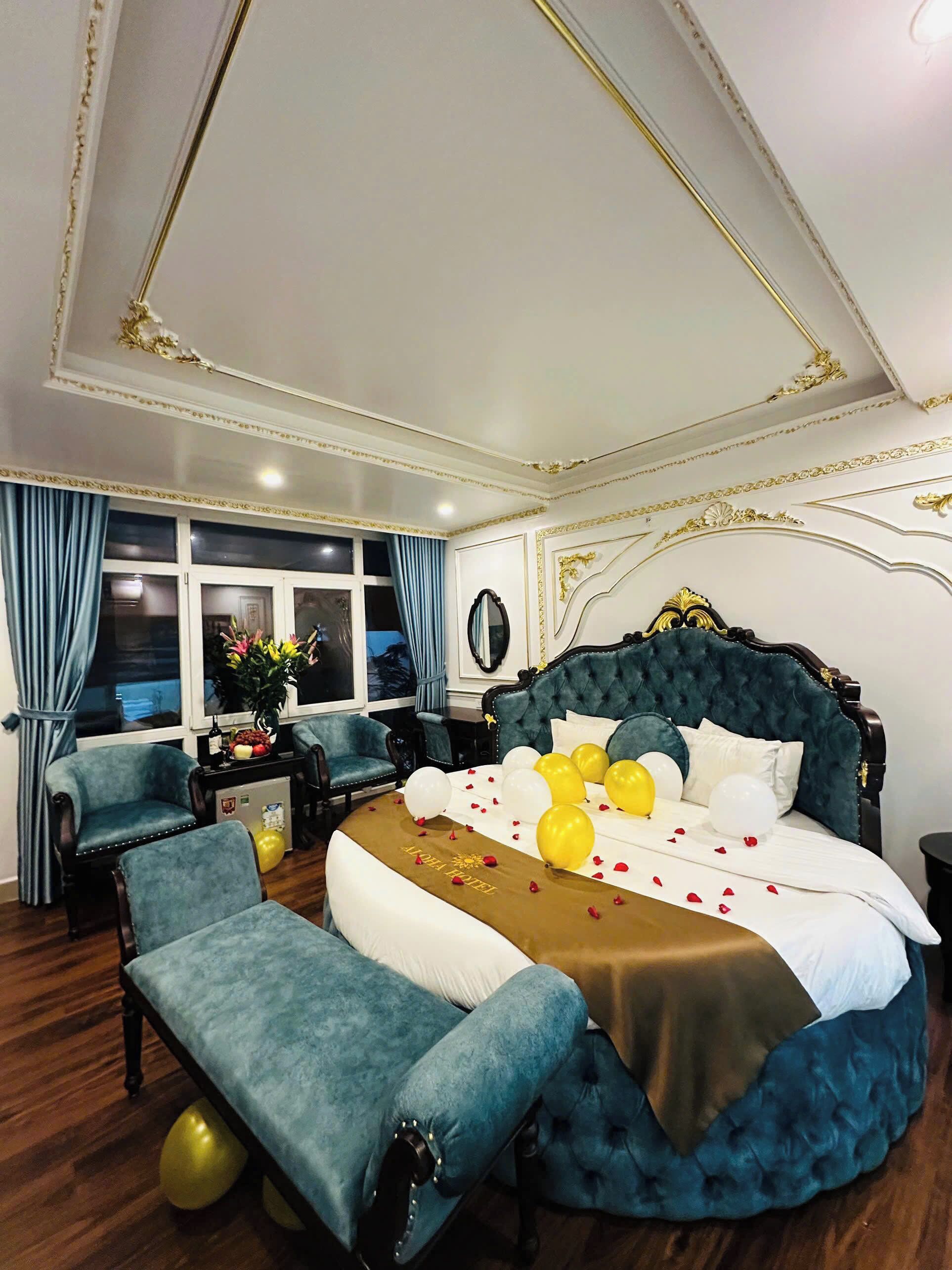 Een luxueuze slaapkamer met een groot bed, een zithoek met stoelen en een uitzicht op de stad door grote ramen.