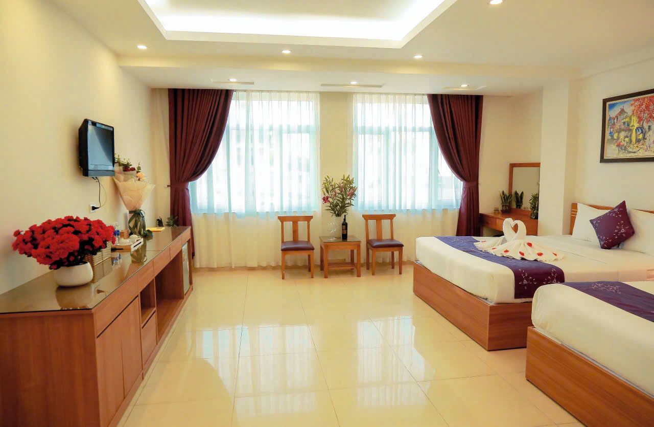 A hotel room with a bed, a desk, a chair, a TV, and a window with curtains.