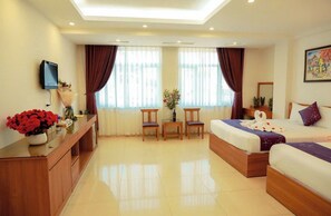 A hotel room with a bed, a desk, a chair, a TV, and a window with curtains. - Aloha Hotel (Hanoi)