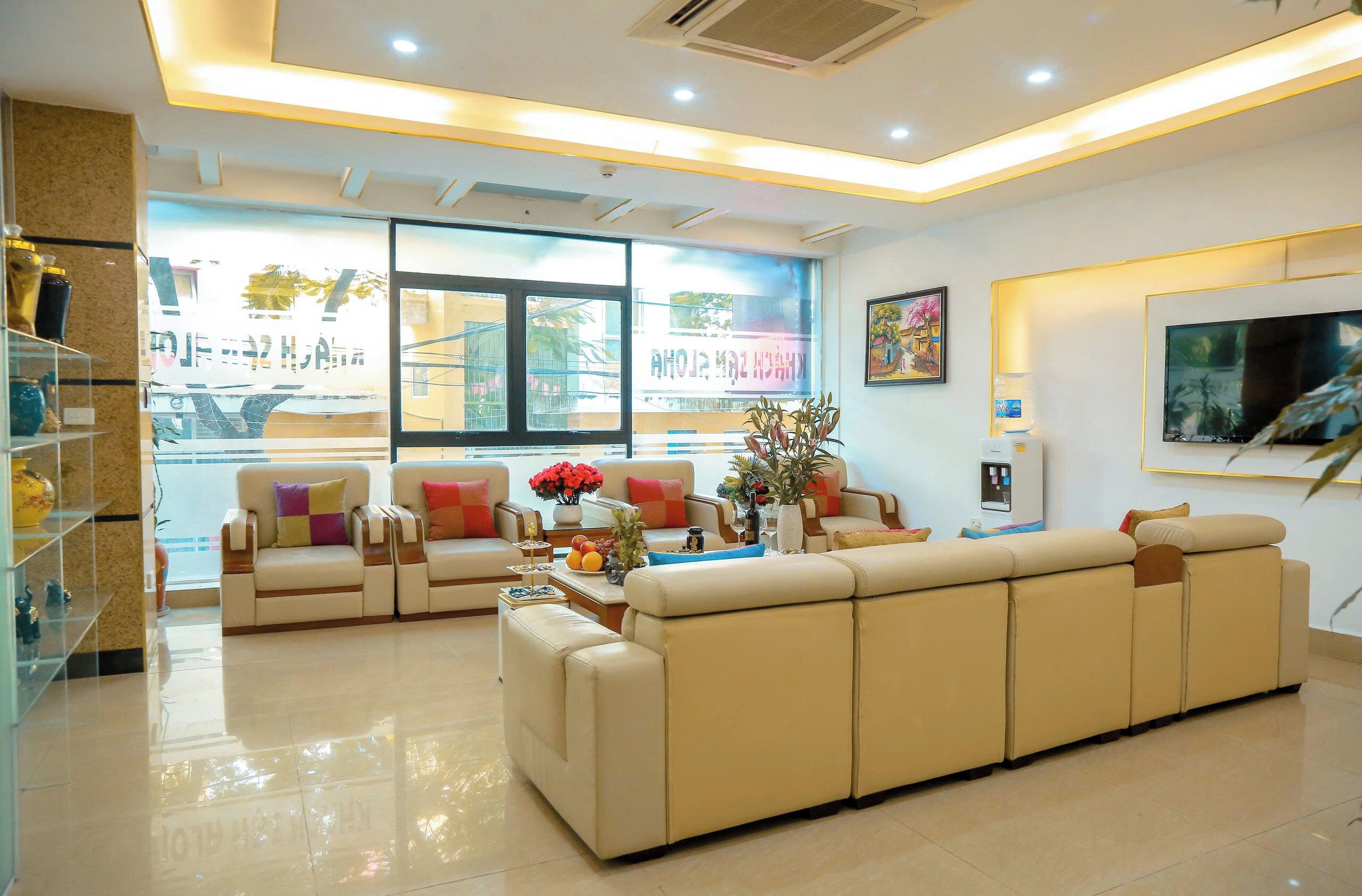 A modern living room with a large beige sofa, a coffee table, and a TV on the wall.