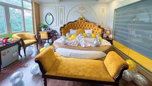 A luxurious bedroom with a large bed, a sofa, a desk, and a large window. - Aloha Hotel (Hanoi)