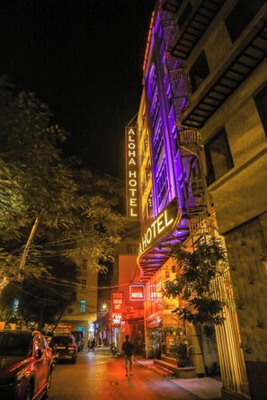 A hotel with a prominent neon sign, a fire escape, and a street view at night. - Aloha Hotel (Hanoi)