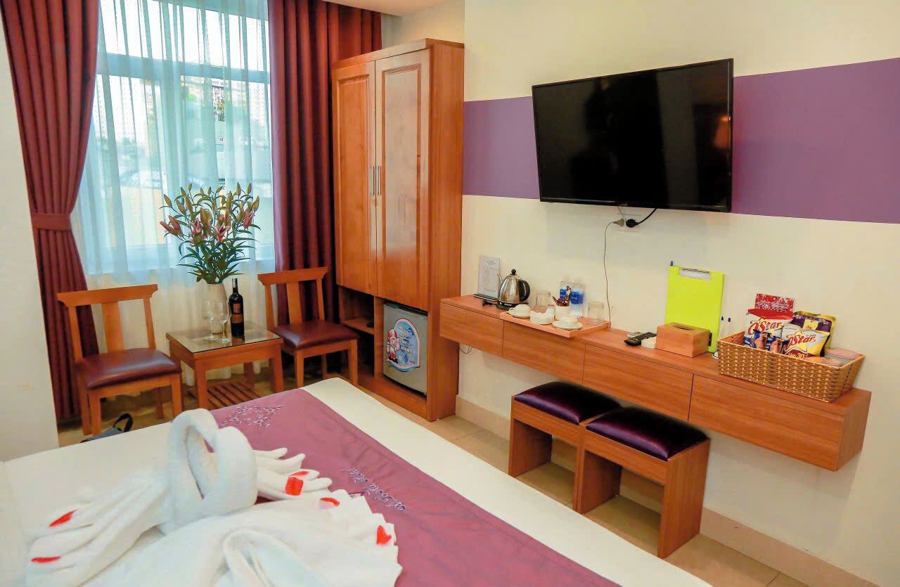 Ein Hotelzimmer mit einem Bett, einem Schreibtisch, einem Fernseher, einem Kleiderschrank und einem Vorhangfenster.