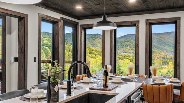 Eine moderne Küche mit einer großen Kochinsel, einer integrierten Spüle und Blick auf eine gebirgige Landschaft durch große Fenster.