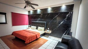 Une chambre à coucher comprenant un lit, une table de chevet, une chaise, un ventilateur de plafond et un mur en marbre.