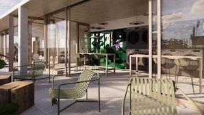 An outdoor seating area with modern chairs and tables, large windows, and a green wall with abstract art. - Lyf Bondi Junction Sydney (Bondi Junction)