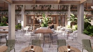 An outdoor dining area with a central wooden table surrounded by chairs, a stone floor, and greenery. - Lyf Bondi Junction Sydney (Bondi Junction)
