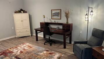 A room with a desk, chair, wardrobe, rug, and a ceiling fan.