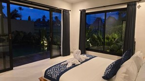 A hotel room with a large bed, a view of a pool and greenery, and a sliding glass door. - Adyatma Ubud (Ubud)