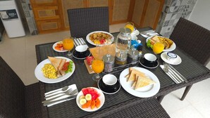 A breakfast table set with plates of scrambled eggs, toast, fruit, and juice. - Adyatma Ubud (Ubud)