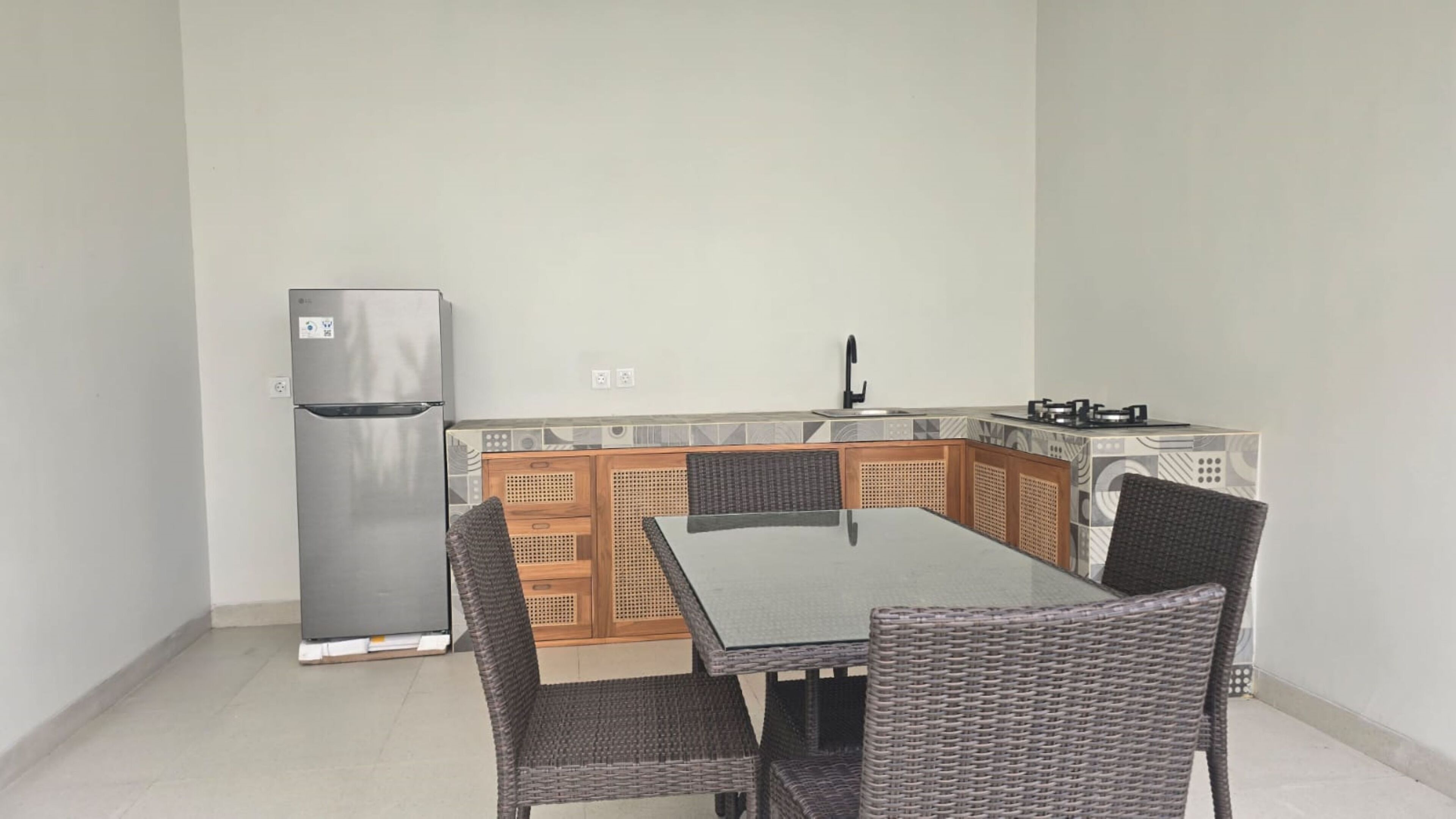 A compact kitchen with a refrigerator, a gas stove, and a dining table with chairs.