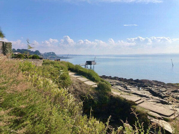 A coastal landscape with a stone pathway leading to a viewing platform overlooking the sea.