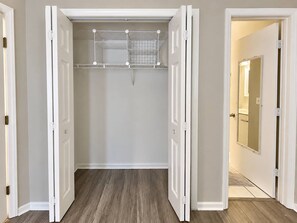 Un dressing accessible sans porte, avec un plancher en bois et une porte de placard miroir.